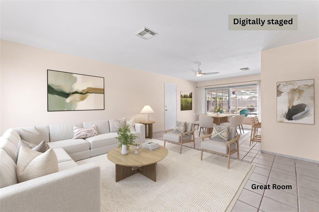 This digitally staged great room features a light-colored sofa, area rug, and tile flooring — 341 W DOVER STREET, SATELLITE BEACH, FL