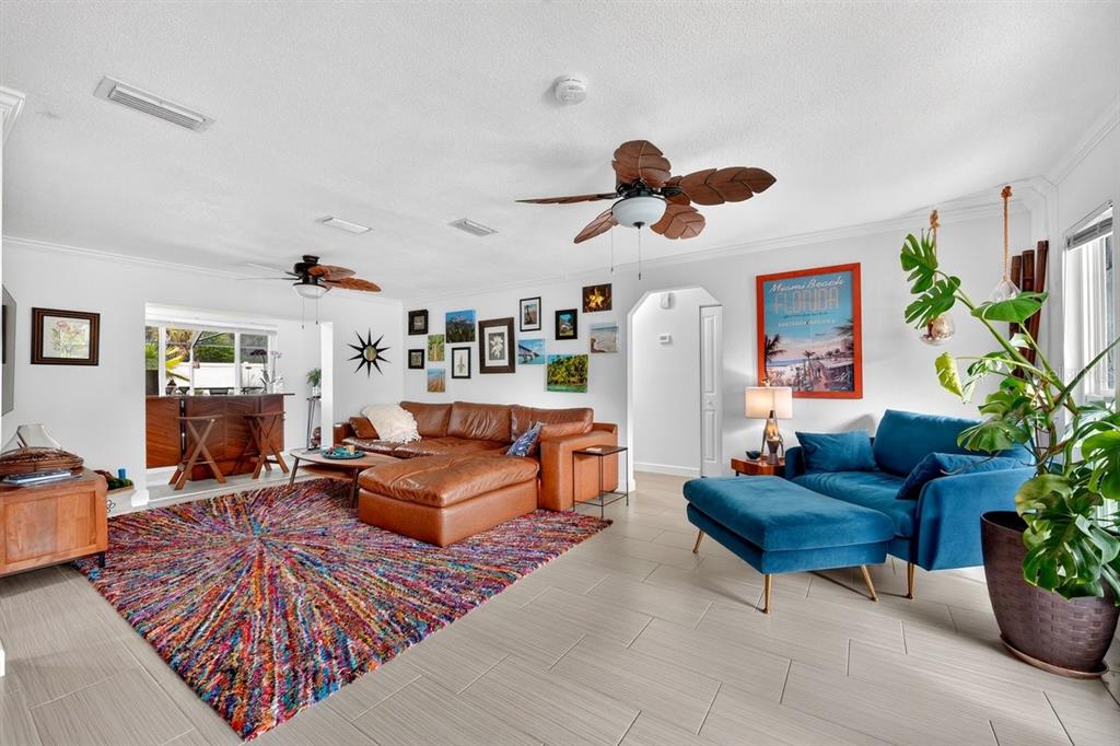 A living room features a brown leather sectional, blue chaise, colorful rug, and tiled floors — 237 BRITTANY AVENUE, PORT ORANGE, FL