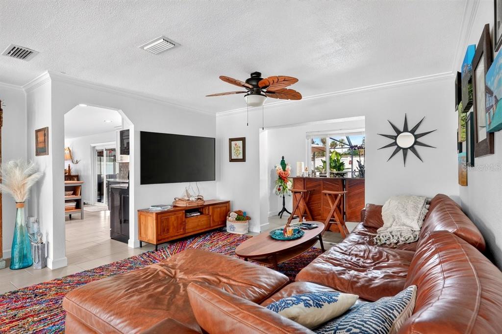 A living room features a brown leather sectional, a wooden media console, and a ceiling fan — 237 BRITTANY AVENUE, PORT ORANGE, FL