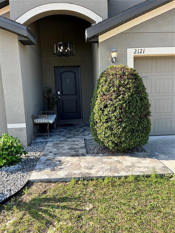 The exterior view shows a front entrance with a stone walkway, a bench, and landscaping — 2121 HIBISCUS PLACE, KISSIMMEE, FL