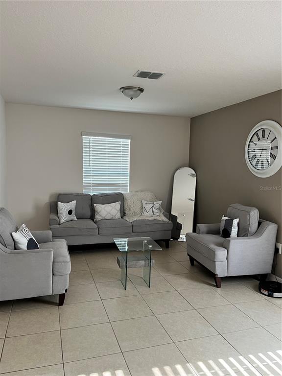 A living room features gray furniture, a glass coffee table, and a large wall clock — 2121 HIBISCUS PLACE, KISSIMMEE, FL