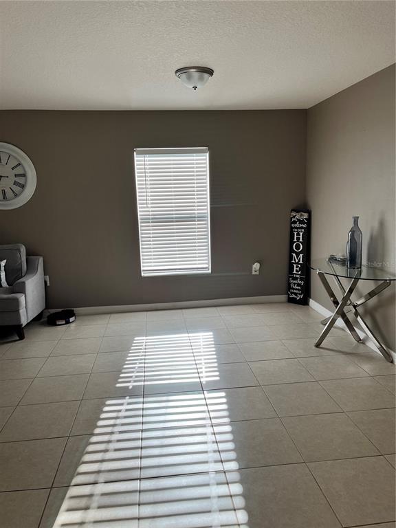 A living room features light tile floors, a window with blinds, and a glass side table — 2121 HIBISCUS PLACE, KISSIMMEE, FL
