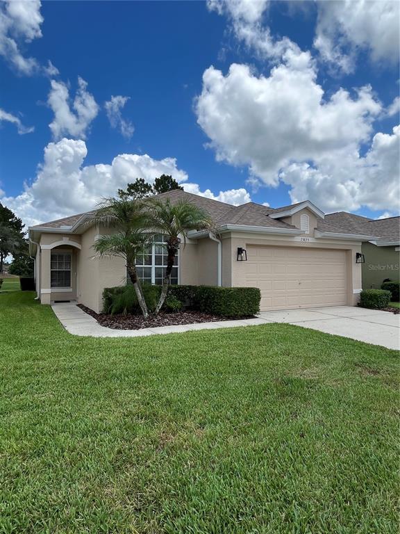 An exterior view of a tan house with a white front door and arched entryway — 23835 CORAL RIDGE LANE, LAND O LAKES, FL