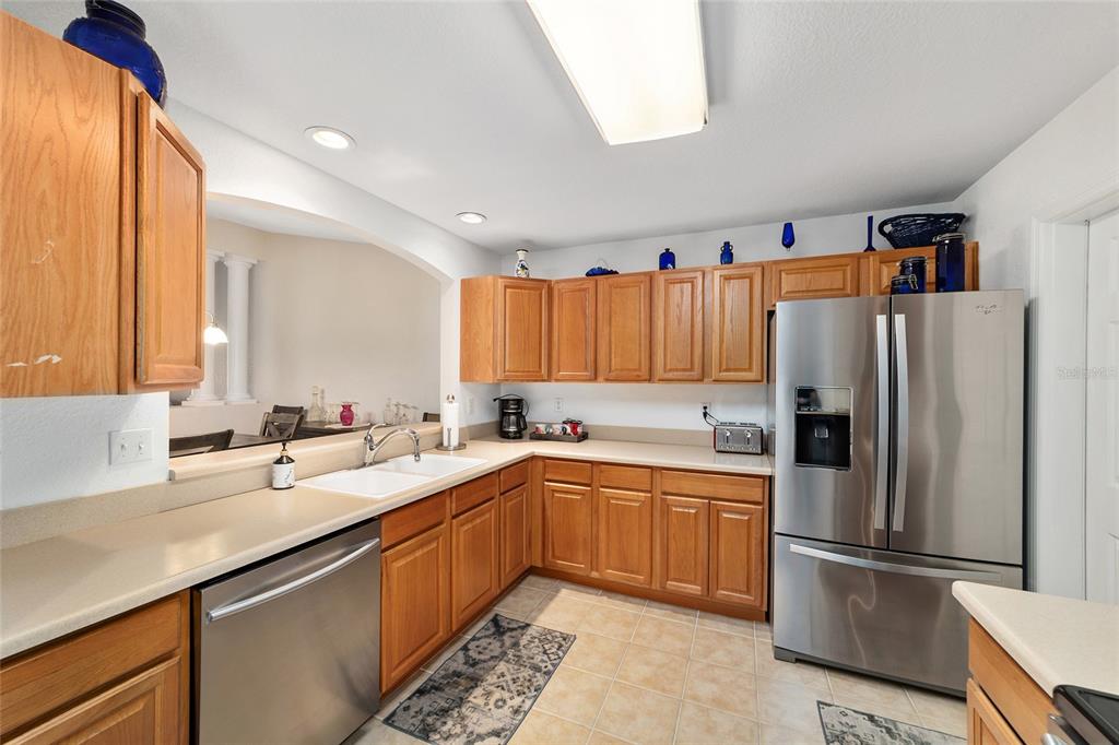 A kitchen features light wood cabinets, stainless steel appliances, and beige countertops — 13640 SW 115TH AVENUE, DUNNELLON, FL