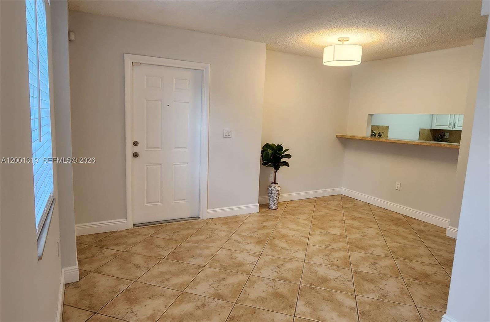 A dining area features tile floors, a white door, and a kitchen pass-through window — 29 Santillane Ave # 2, Coral Gables FL 33134, CORAL GABLES, FL