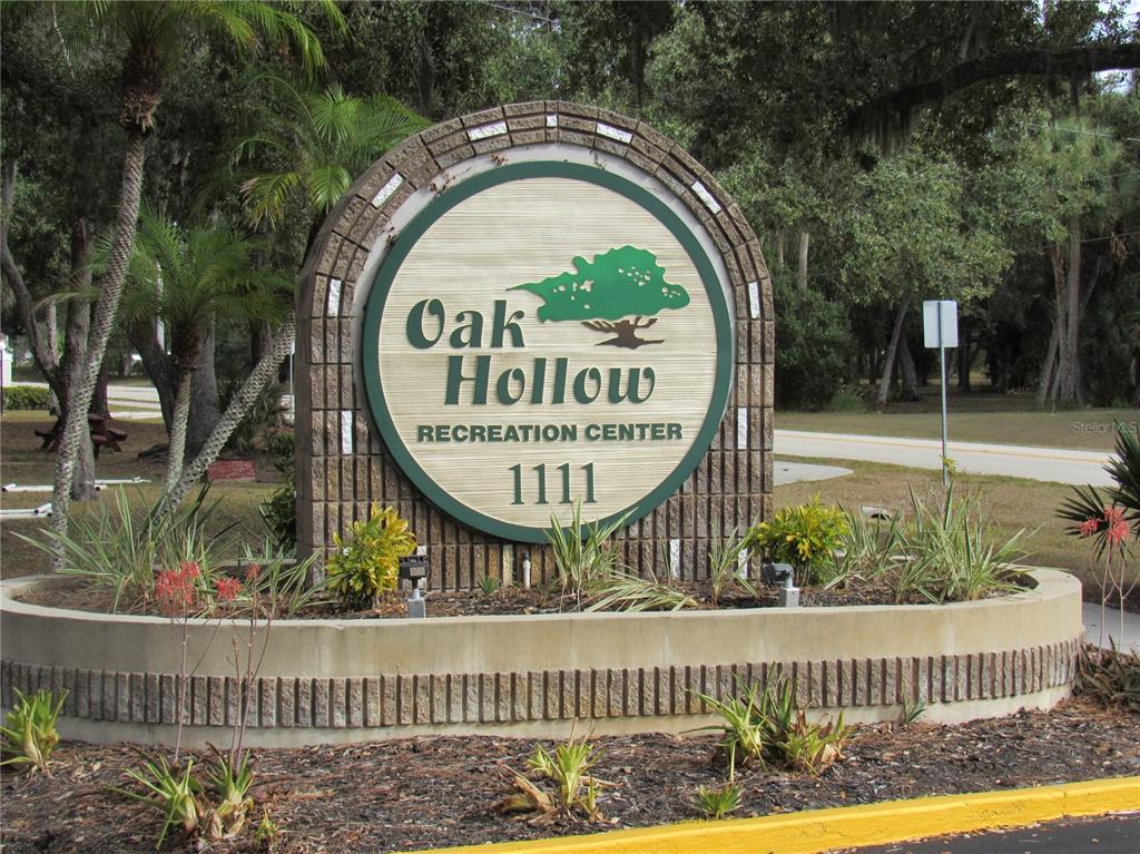 A circular sign for the Oak Hollow Recreation Center stands in a landscaped garden bed — 20005 GOLDCUP COURT, PORT CHARLOTTE, FL