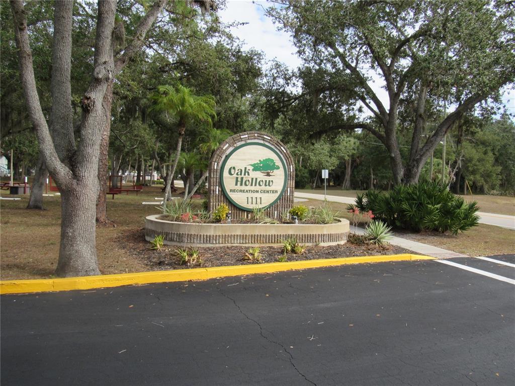 A circular sign for the Oak Hollow Recreation Center stands in a landscaped garden area — 20005 GOLDCUP COURT, PORT CHARLOTTE, FL