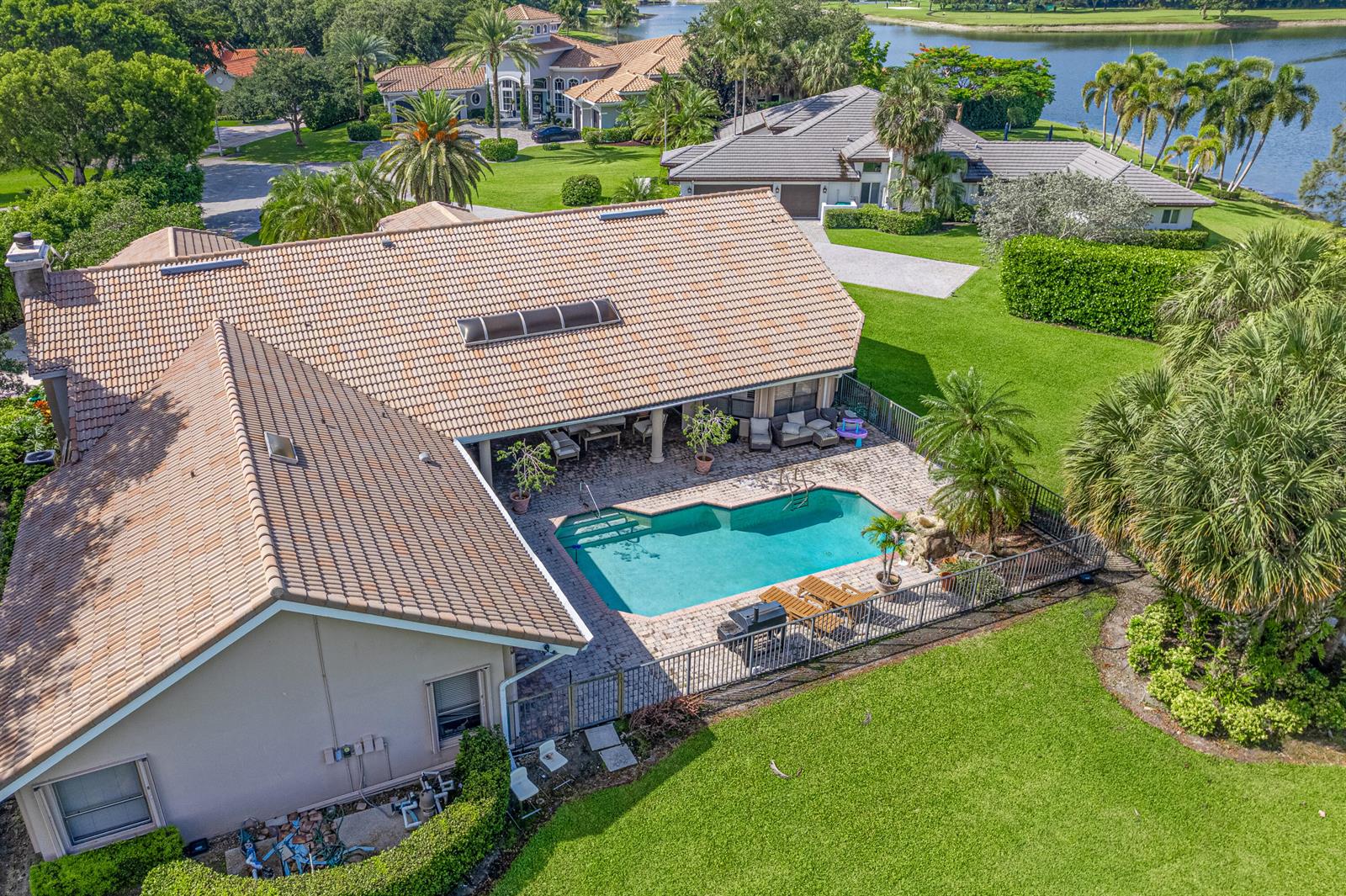 An aerial view of a house with a tiled roof, swimming pool, and backyard lawn — 7511 Brigantine Lane, Parkland FL 33067, PARKLAND, FL