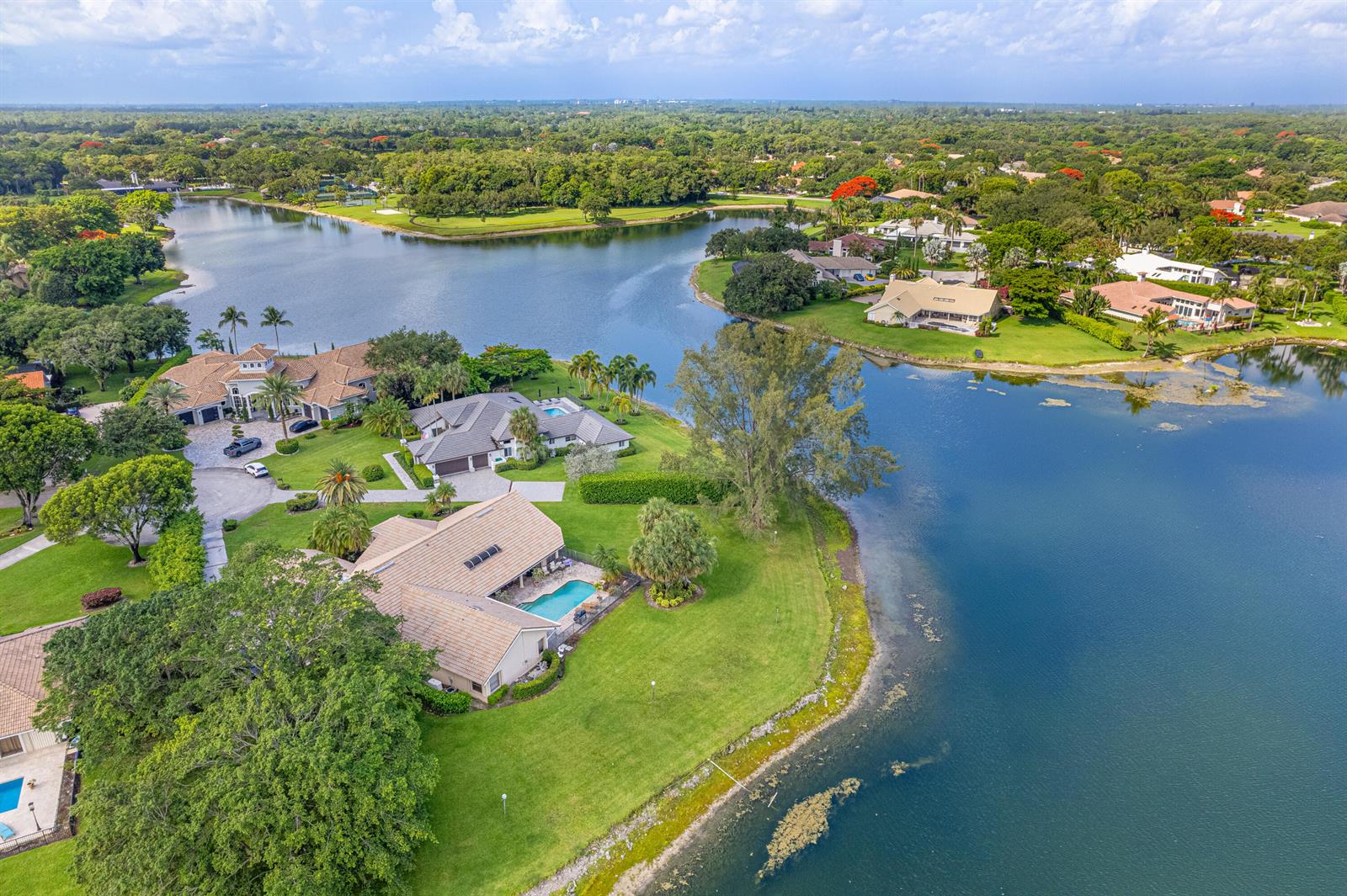 An aerial view shows several waterfront houses with swimming pools surrounded by lush green lawns — 7511 Brigantine Lane, Parkland FL 33067, PARKLAND, FL