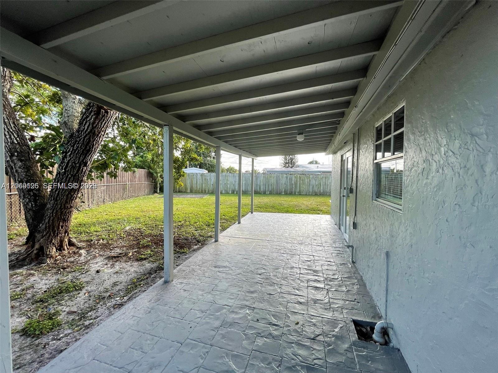 A covered concrete patio overlooks a fenced backyard with a large tree — 4160 SW 36th St, West Park FL 33023, WEST PARK, FL