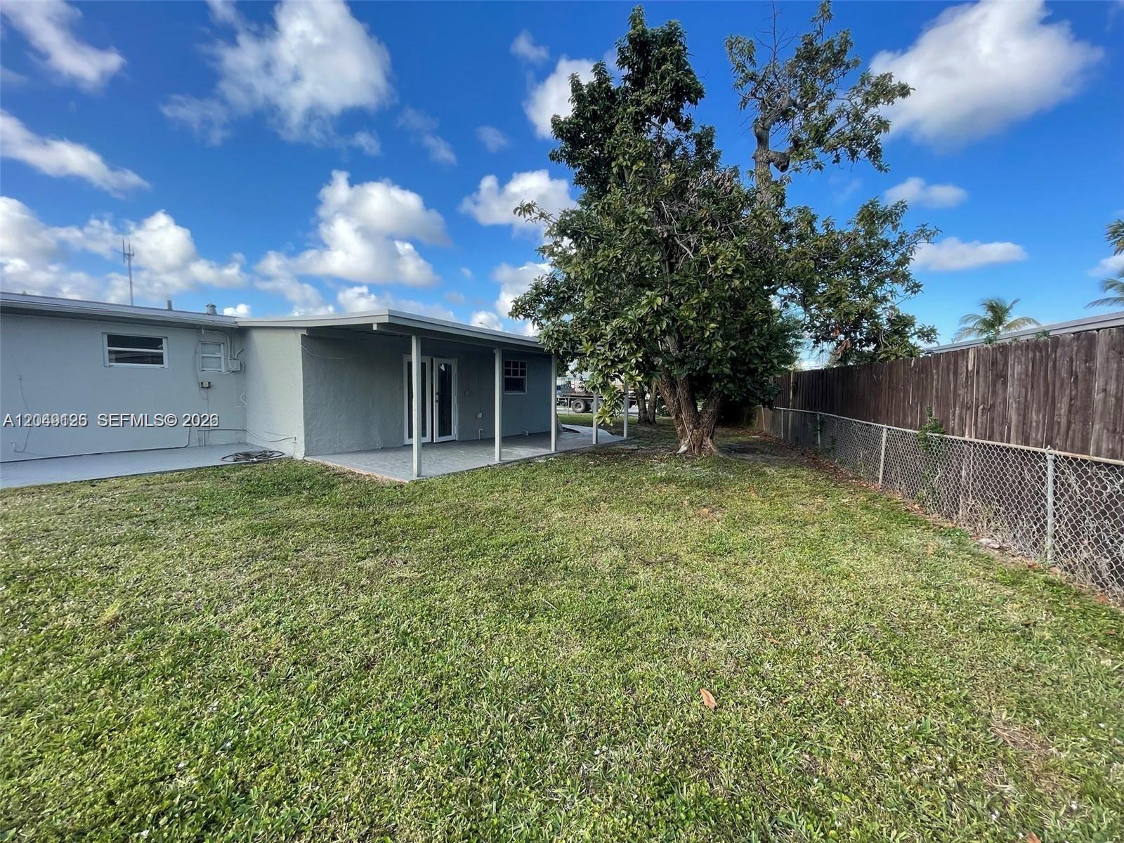 A backyard features a covered patio, a large tree, and a wooden fence — 4160 SW 36th St, West Park FL 33023, WEST PARK, FL