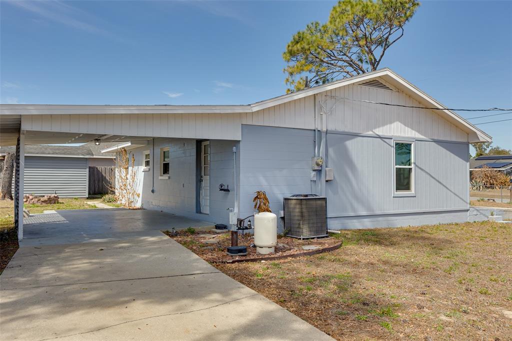 A light blue house with a concrete driveway, a carport, and an outdoor air conditioning unit — 9782 SE 157TH LANE, SUMMERFIELD, FL