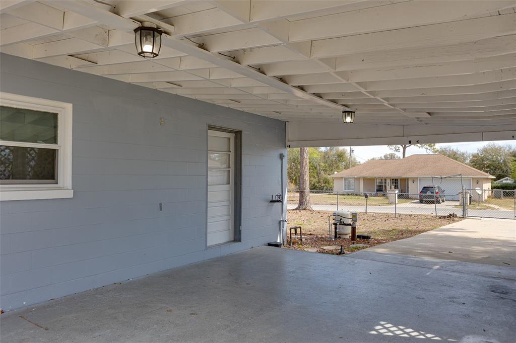 A concrete carport with a white ceiling, two light fixtures, and a gray block wall — 9782 SE 157TH LANE, SUMMERFIELD, FL
