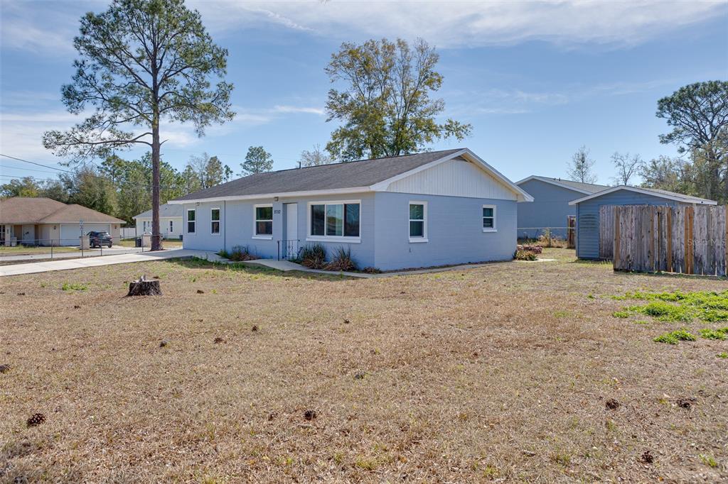 A light blue single-story house with a white gable sits on a dry, grassy lot — 9782 SE 157TH LANE, SUMMERFIELD, FL