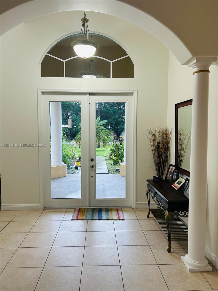 An entryway features double glass doors, a tiled floor, a decorative column, and a chandelier — 13754 N 48th Ct N, West Palm Beach FL 33411, WEST PALM BEACH, FL