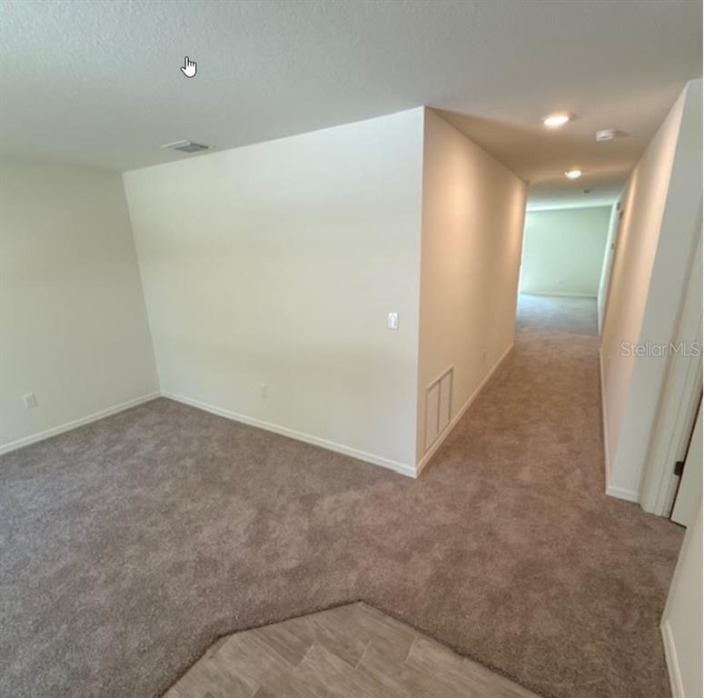 An interior view shows a carpeted room with a hallway leading to another space — 37 PACKARD LANE, PALM COAST, FL