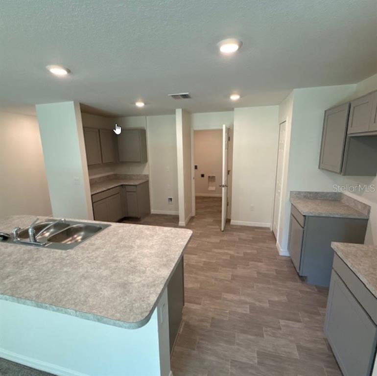 A kitchen with gray cabinets, laminate countertops, an island sink, and light-colored tile flooring — 37 PACKARD LANE, PALM COAST, FL