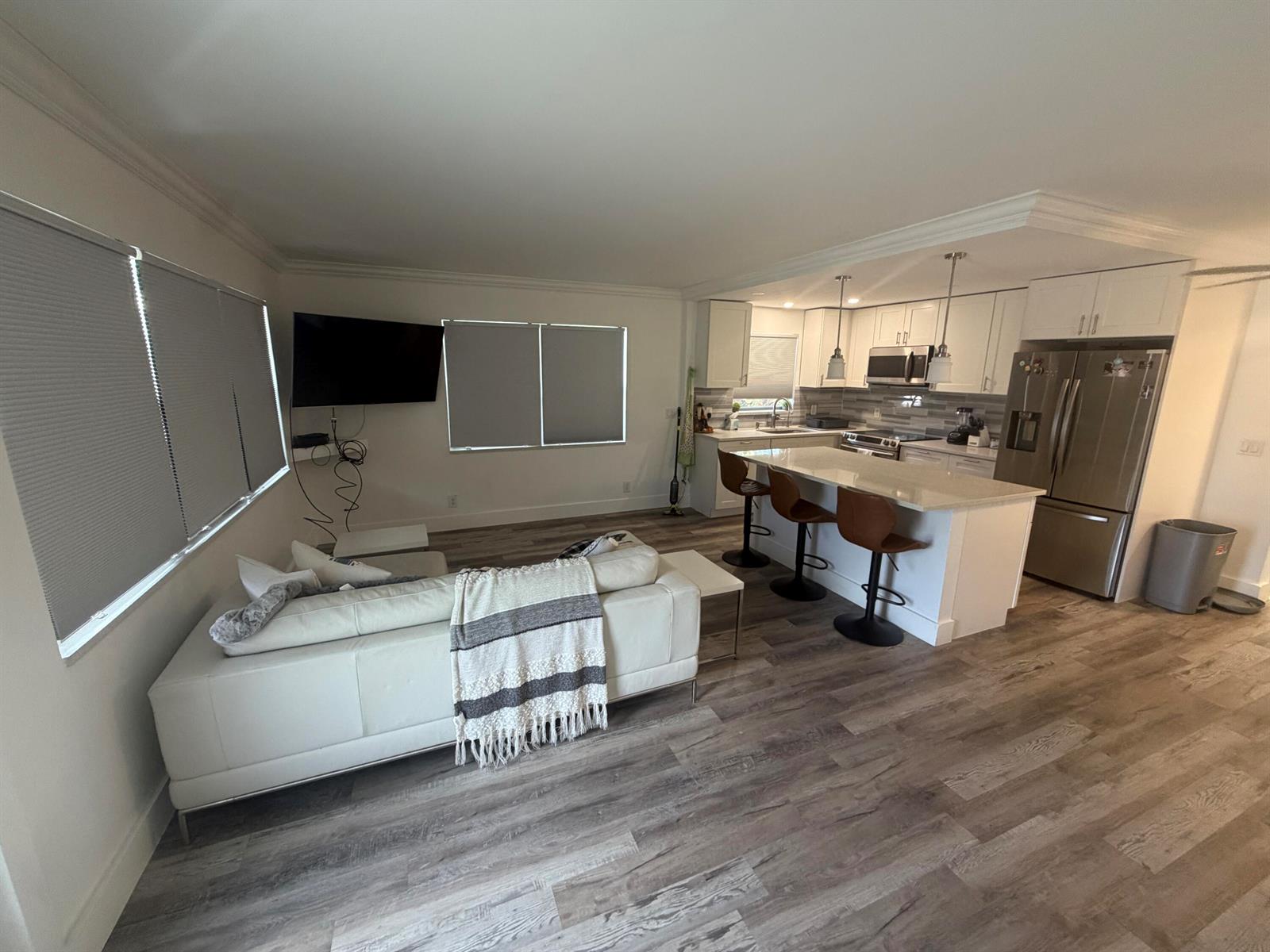 An open-concept living room and kitchen featuring white cabinetry, a kitchen island, and wood-look flooring — 209 Newport M # 209, Deerfield Beach FL 33442, DEERFIELD BEACH, FL