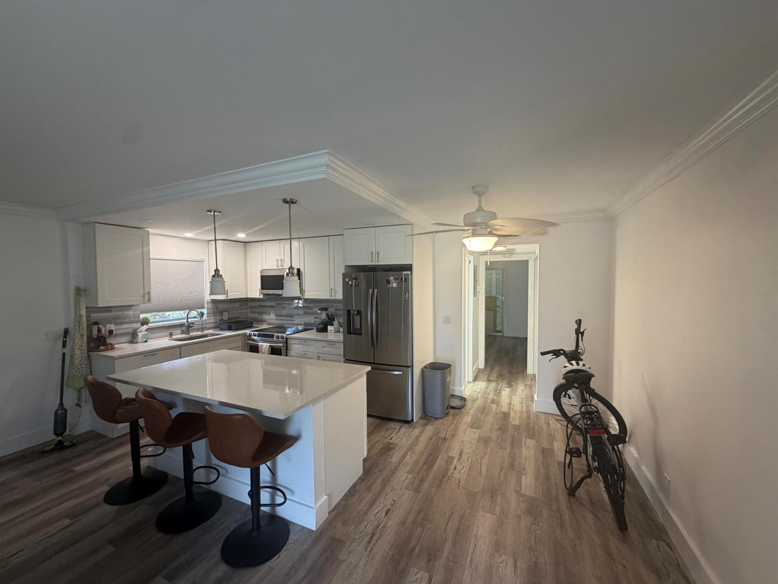 A kitchen with white cabinets, a quartz island, stainless steel appliances, and wood-look flooring — 209 Newport M # 209, Deerfield Beach FL 33442, DEERFIELD BEACH, FL