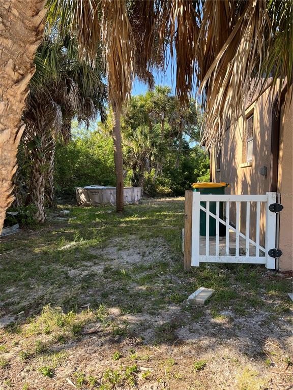 A side yard features a white gate, a green trash bin, and a small above-ground pool — 15532 CHAMBERLAIN BOULEVARD UNIT A, PORT CHARLOTTE, FL