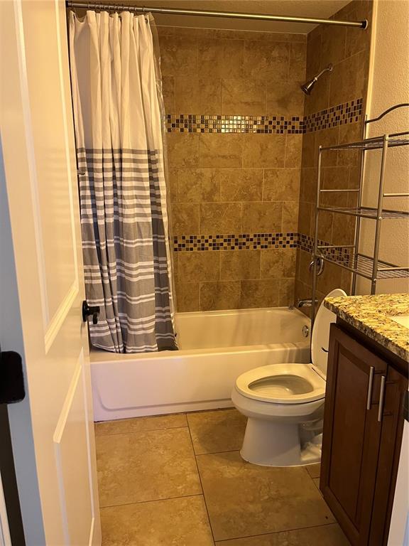 A bathroom features a tiled tub-shower combination, a white toilet, and a wooden vanity — 15532 CHAMBERLAIN BOULEVARD UNIT A, PORT CHARLOTTE, FL