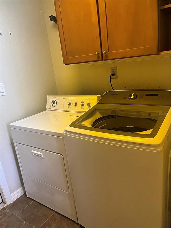 A laundry room features a white dryer, a Samsung top-load washer, and wood wall cabinets — 15532 CHAMBERLAIN BOULEVARD UNIT A, PORT CHARLOTTE, FL