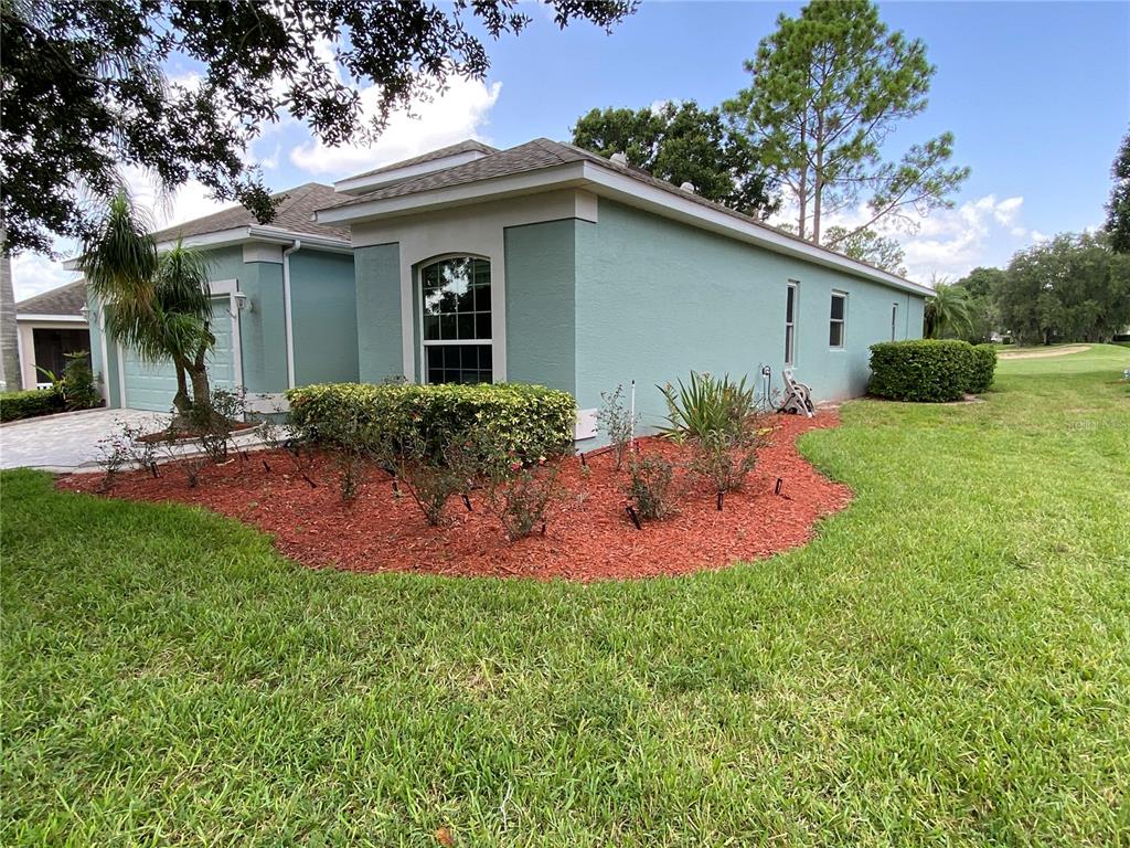 A light blue house exterior features a red mulch garden bed and a green lawn — 4202 HAMMERSMITH DRIVE, CLERMONT, FL