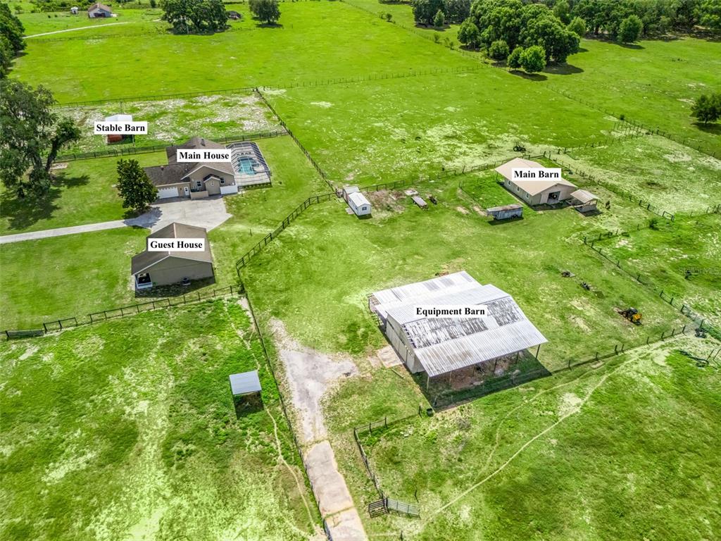 An aerial view shows a rural property with a main house, guest house, and several barns — 2223 CR 543, SUMTERVILLE, FL