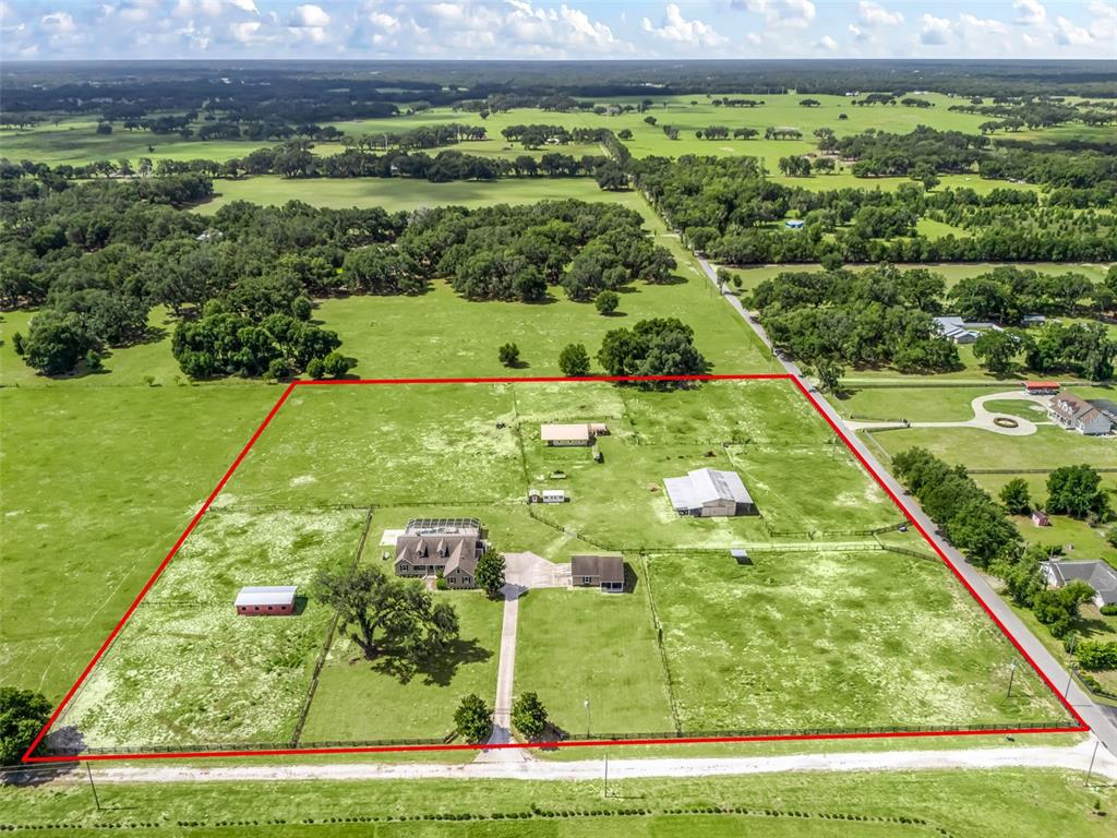 An aerial view shows a rural property with a house, several outbuildings, and fenced pastures — 2223 CR 543, SUMTERVILLE, FL