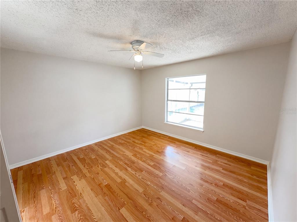 An empty bedroom features light-colored walls, a ceiling fan, and hardwood flooring — 9814 DEAN COVE LANE, ORLANDO, FL
