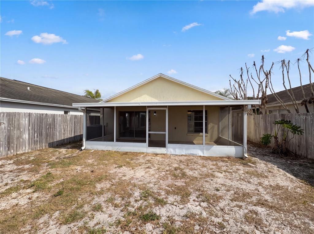 The exterior view shows a yellow house with a screened-in back porch and sandy yard — 9814 DEAN COVE LANE, ORLANDO, FL