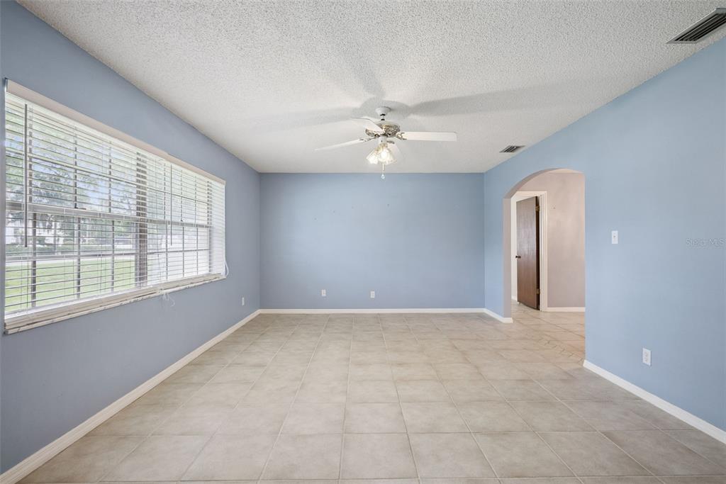 An empty room with light blue walls, tile flooring, a ceiling fan, and arched entryway — 1452 DINGENS AVENUE, WINDERMERE, FL