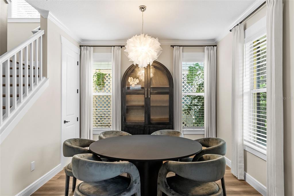 A dining room features a round black table, velvet chairs, and a large arched cabinet — 2915 W BAY VIEW AVENUE, TAMPA, FL