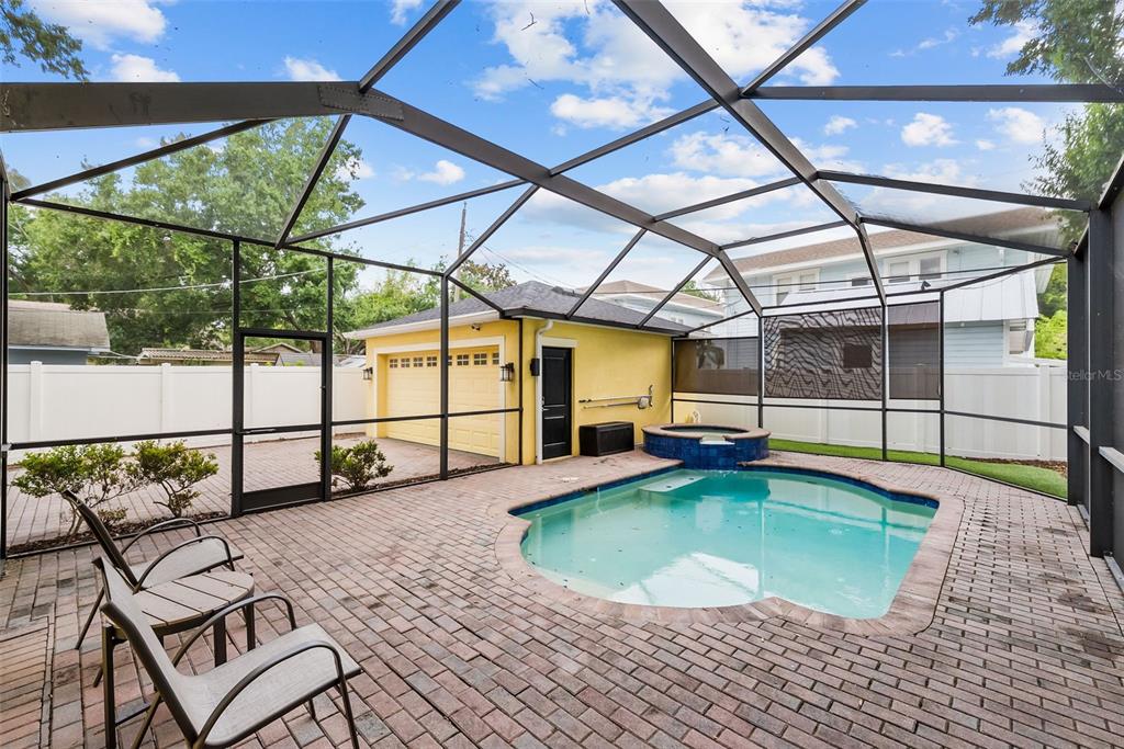 A screened-in patio features a brick-paved deck, a swimming pool, and a detached yellow garage — 2915 W BAY VIEW AVENUE, TAMPA, FL