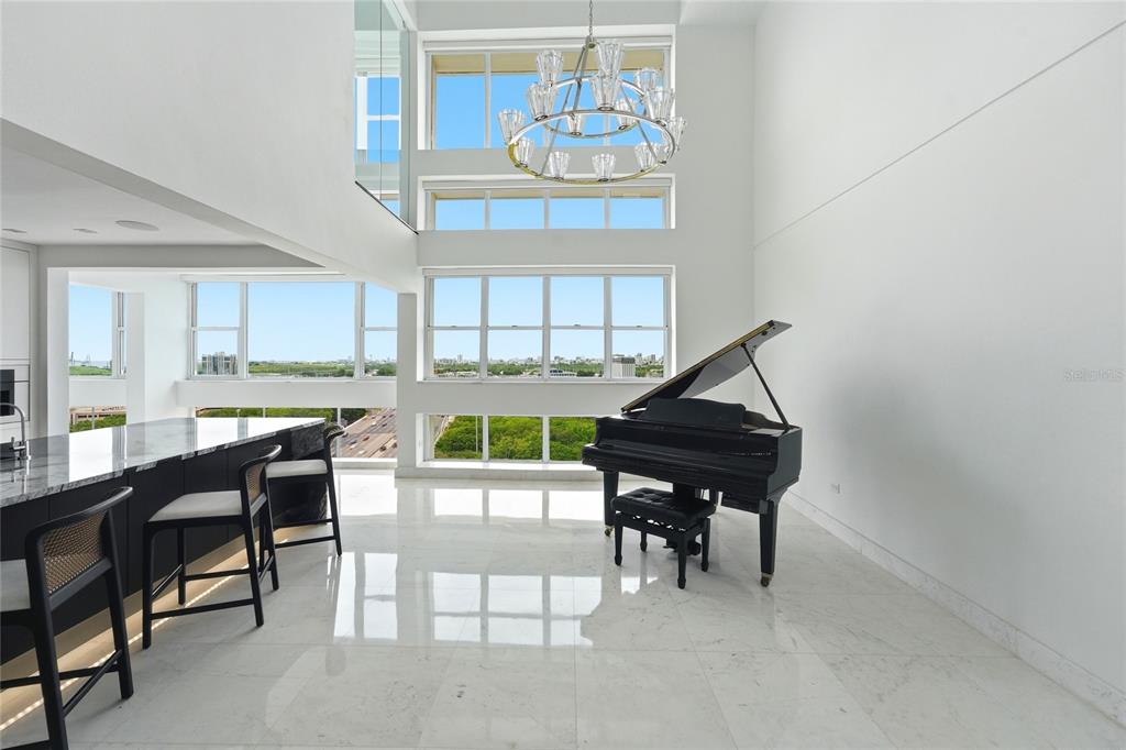 A modern, high-ceilinged living area features a black grand piano, marble floors, and large windows — Mirador del Parque SERGIO CUEVAS & JUAN B. RODRIGUEZ UNIT 17, SAN JUAN, PR