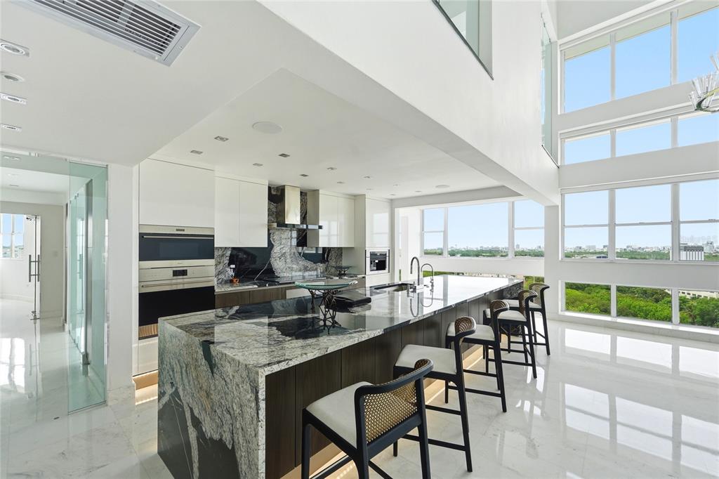 A modern kitchen features a large marble island, dark cabinetry, and floor-to-ceiling windows — Mirador del Parque SERGIO CUEVAS & JUAN B. RODRIGUEZ UNIT 17, SAN JUAN, PR