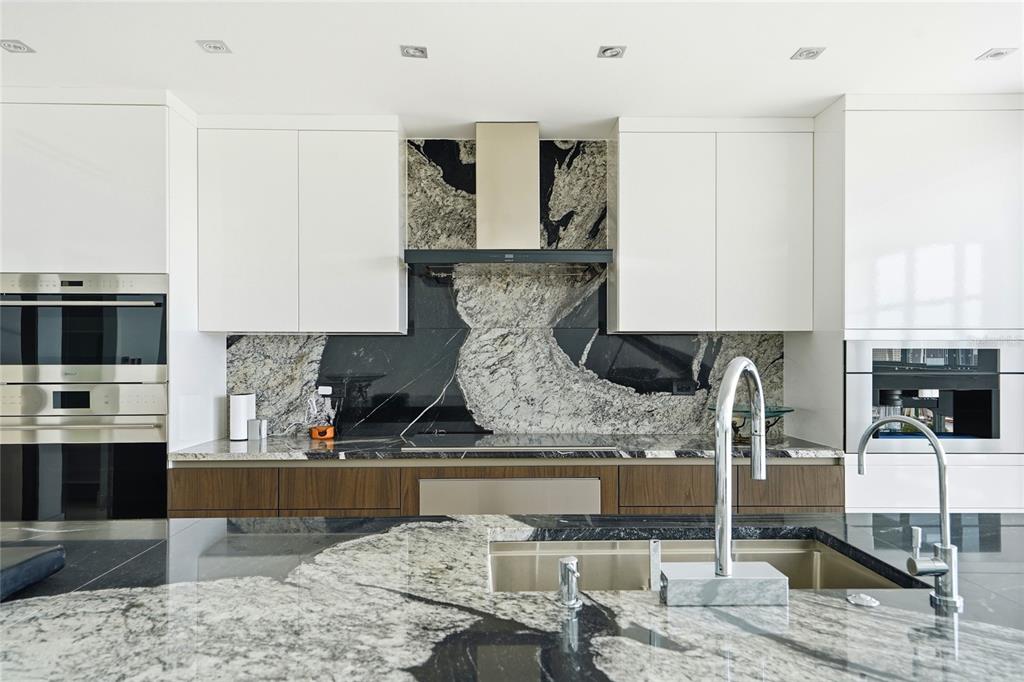 A modern kitchen features white upper cabinets, wood lower cabinets, and dramatic black and white stone — Mirador del Parque SERGIO CUEVAS & JUAN B. RODRIGUEZ UNIT 17, SAN JUAN, PR