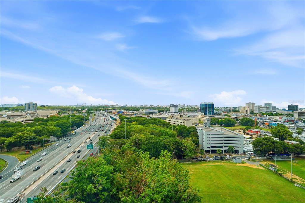 An elevated view shows a multi-lane highway running alongside a large green field — Mirador del Parque SERGIO CUEVAS & JUAN B. RODRIGUEZ UNIT 17, SAN JUAN, PR