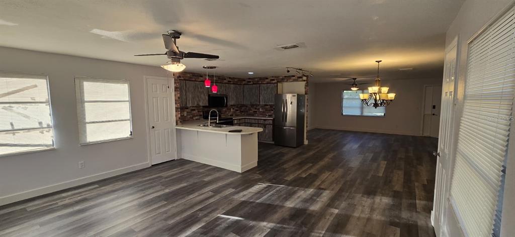 An open-concept kitchen and living area features wood-look flooring, a breakfast bar, and stainless appliances — 1174 VICTORIA AVENUE, PORT CHARLOTTE, FL