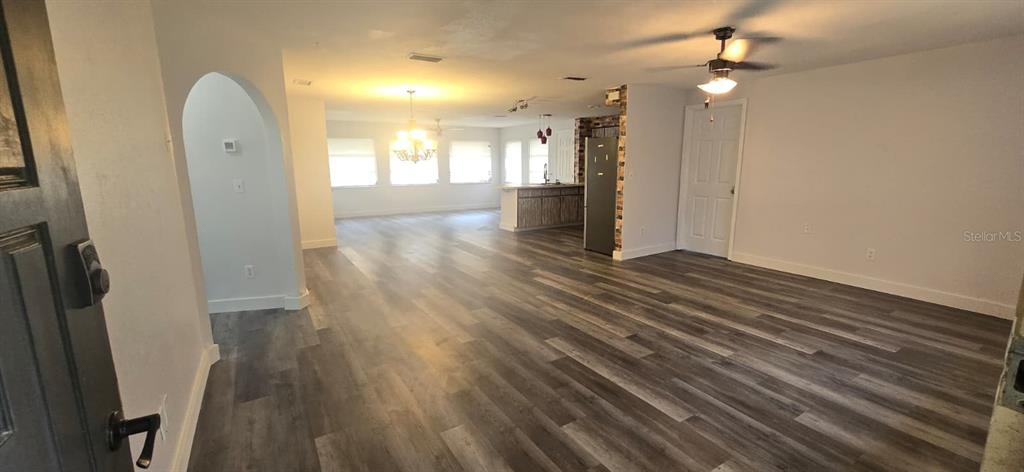 An open-concept living and dining area features wood-look flooring and a kitchen with brick accents — 1174 VICTORIA AVENUE, PORT CHARLOTTE, FL