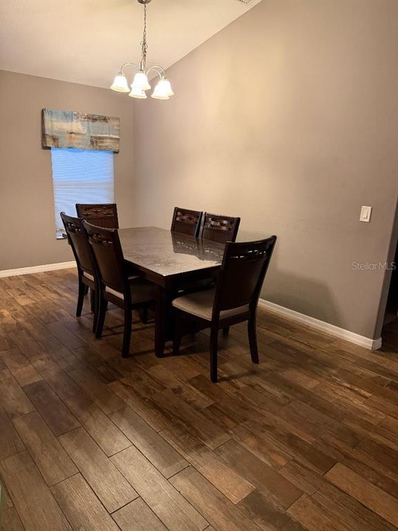 A dining room features a dark wood table with six chairs and wood-look tile flooring — 2212 GAMEWELL COURT, DELTONA, FL