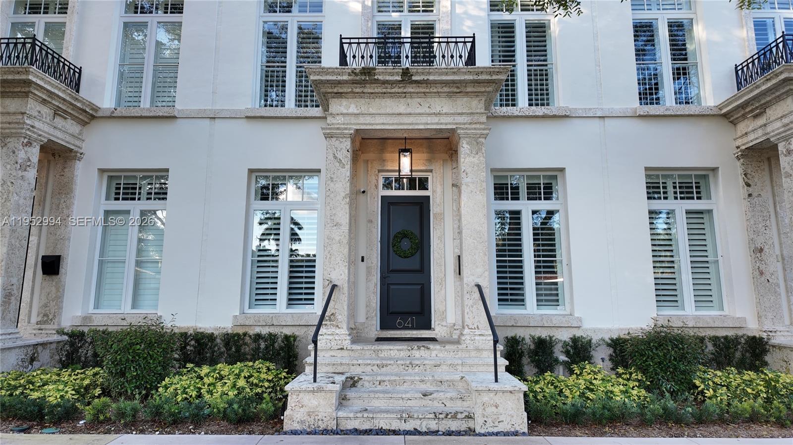 The exterior of a white multi-story building features a stone-framed entrance with a black door — 641 Almeria Ave, Coral Gables FL 33134, CORAL GABLES, FL