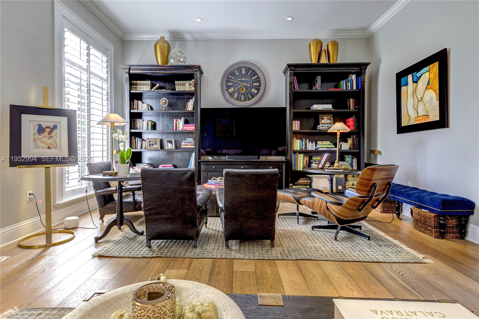 A living room features dark wood bookshelves, a large wall clock, and leather seating — 641 Almeria Ave, Coral Gables FL 33134, CORAL GABLES, FL