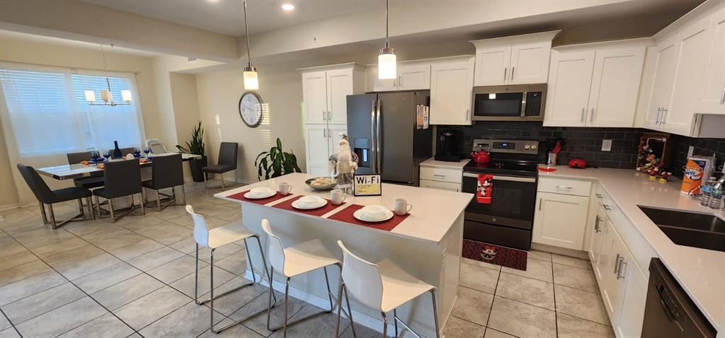 A kitchen with white cabinets, a central island, and an adjacent dining area — 3150 PARADOX CIRCLE UNIT 302, KISSIMMEE, FL