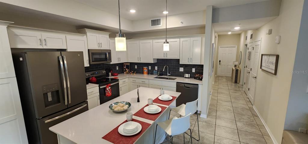 A kitchen features white cabinets, stainless steel appliances, a center island, and tile flooring — 3150 PARADOX CIRCLE UNIT 302, KISSIMMEE, FL