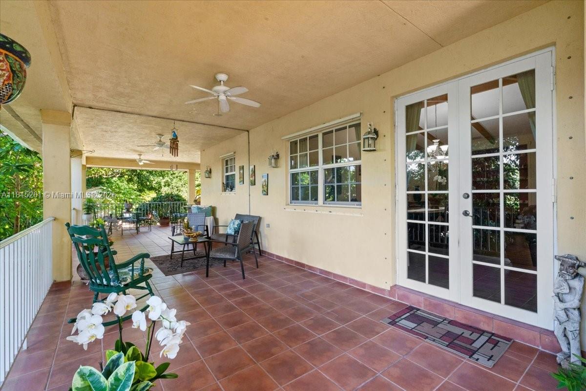 A gravel driveway leads through white metal gates toward a house surrounded by lush trees — 23600 SW 187th Ave, Homestead FL 33031, HOMESTEAD, FL