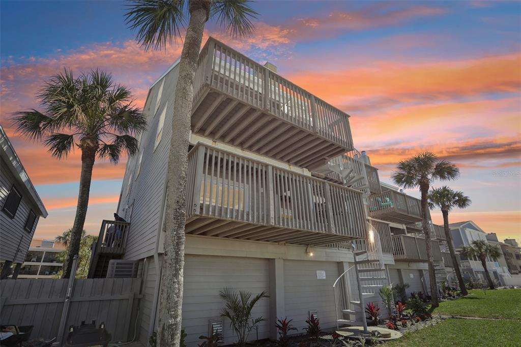 A multi-story coastal home with wooden balconies and a spiral staircase at sunset — 19930 GULF BOULEVARD UNIT 3B, INDIAN SHORES, FL