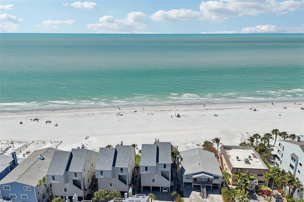 An aerial view shows several multi-story beach houses situated directly along a sandy coastline — 19930 GULF BOULEVARD UNIT 3B, INDIAN SHORES, FL