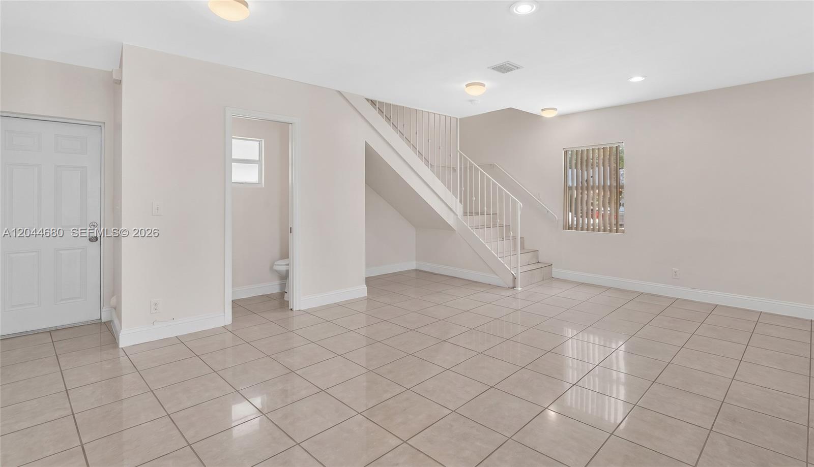 An interior view shows a tiled living area with a staircase and a small bathroom — 1316 NW 3rd St, Fort Lauderdale FL 33311, FORT LAUDERDALE, FL