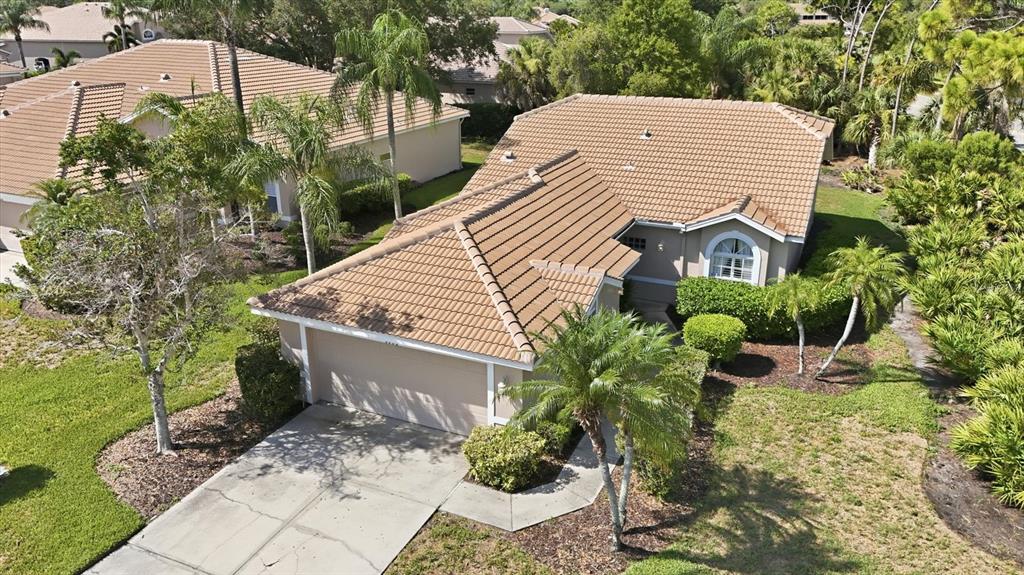 An aerial view of a single-story house with a tan tile roof and driveway — 9402 FOREST HILLS CIRCLE, SARASOTA, FL